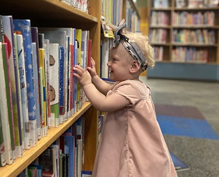 Small child pulling books from shelf